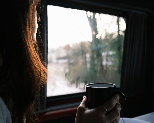 Person looking out of a window with soft natural light, taking a break from screen time
